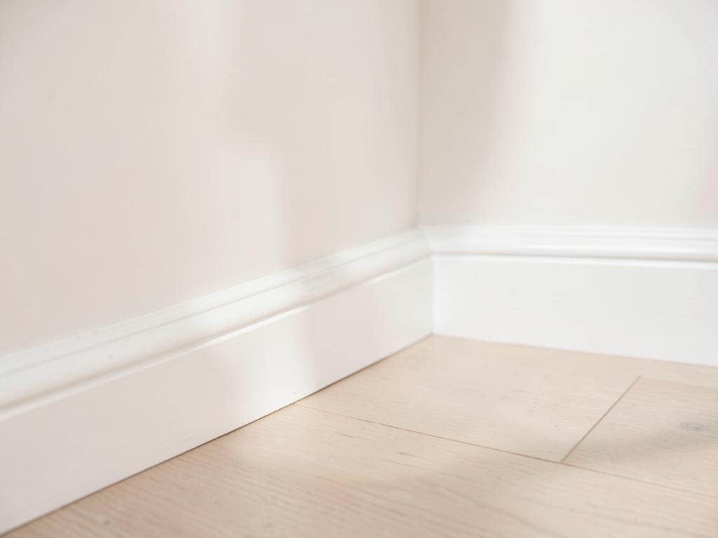 Freshly painted white wall meeting crisp skirting board