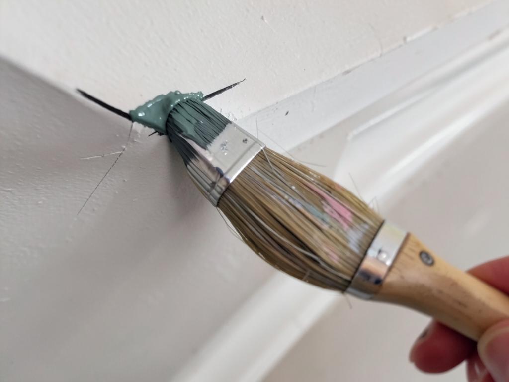 Brush cutting a sharp paint line along a ceiling